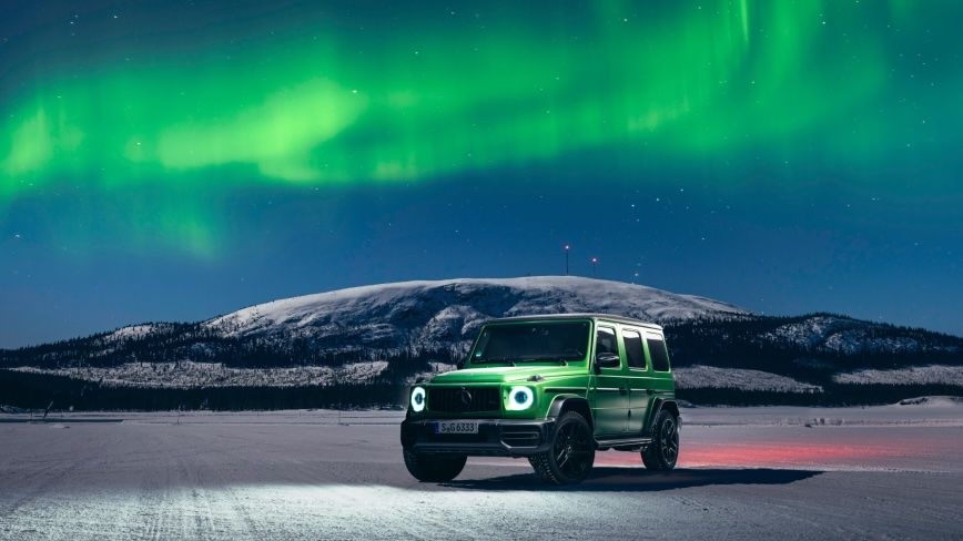 Eine Mercedes-AMG G-Klasse mit Polarlichtern im Hintergrund.