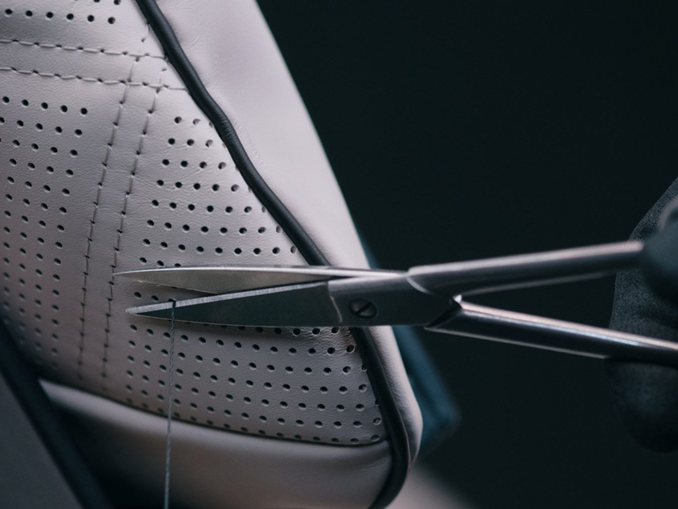 Der Garn eines MANUFAKTUR Kissens wird mit einer Schere abgeschnitten.