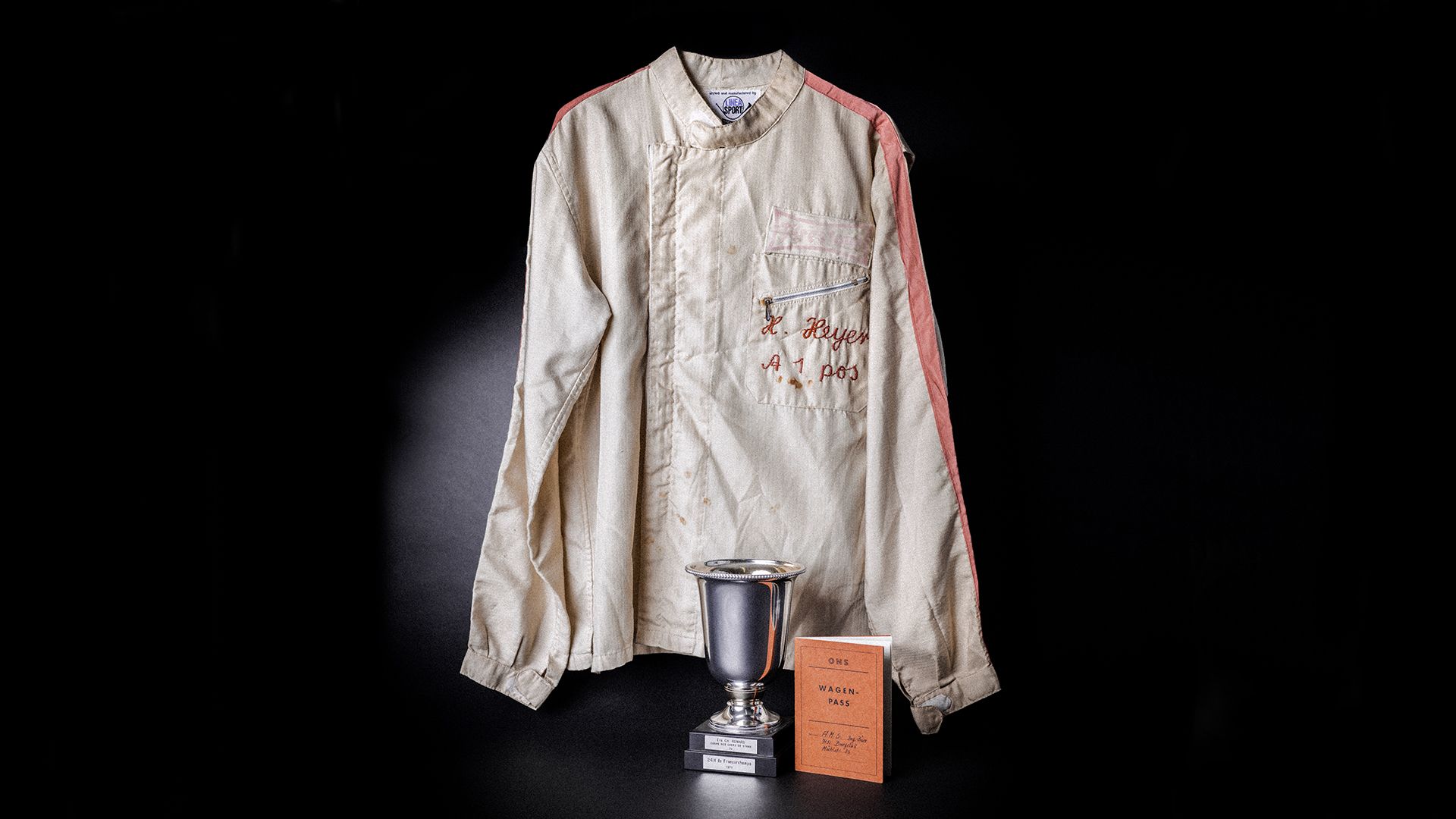 Illustration of a racing suit, a commemorative cup and a booklet